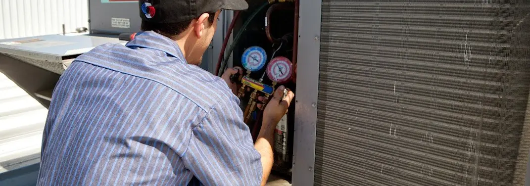 HVAC technician servicing a condenser unit in Arnold